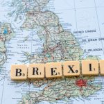 Scrabble letters spelling 'Brexit' with a map of the UK as background