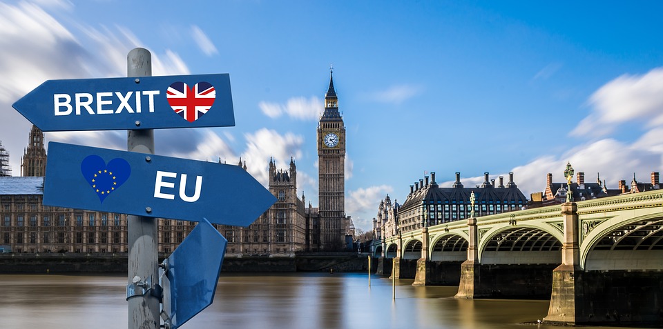 A sign in front of the River Thames and Houses of Parliament with 'Brexit' and 'EU' on it