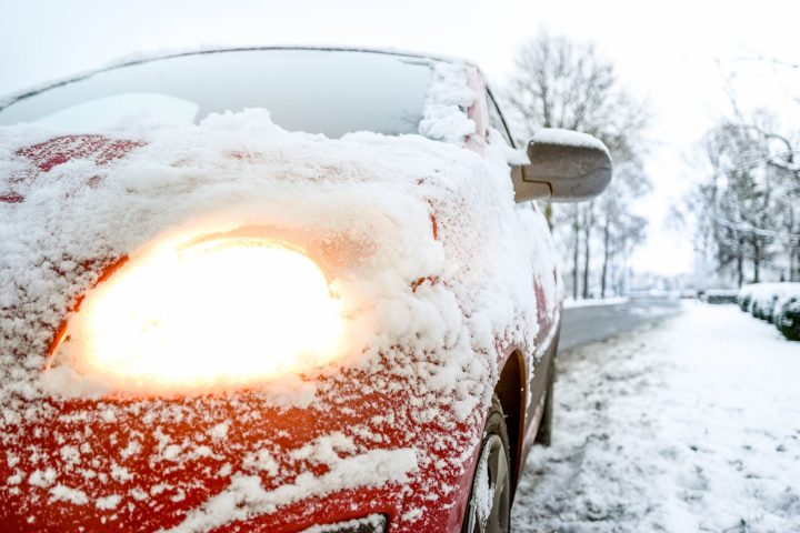 car with snow on the windscreen and with headlights on